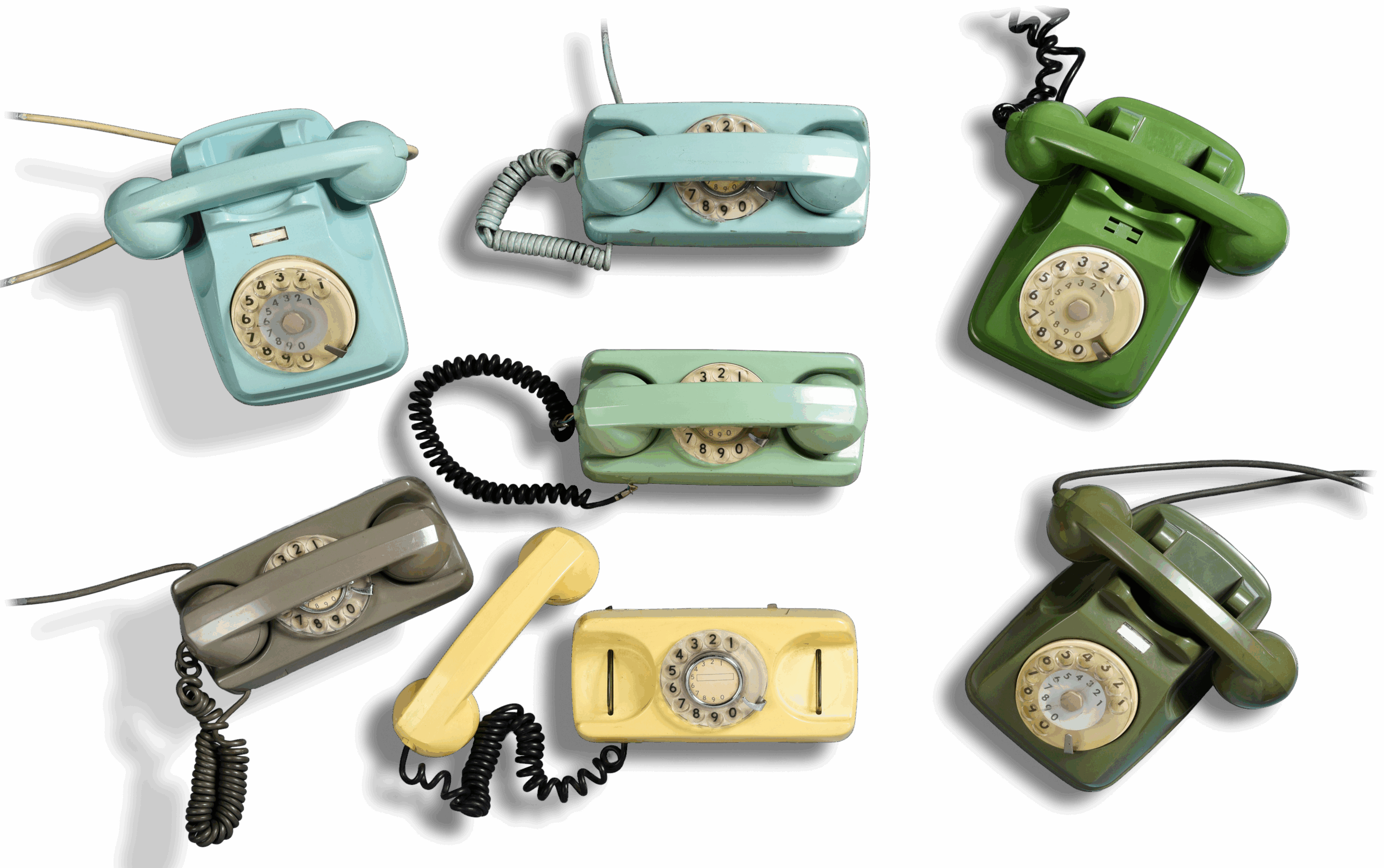 Telefono vintage a disco in vari colori disposti su sfondo neutro.